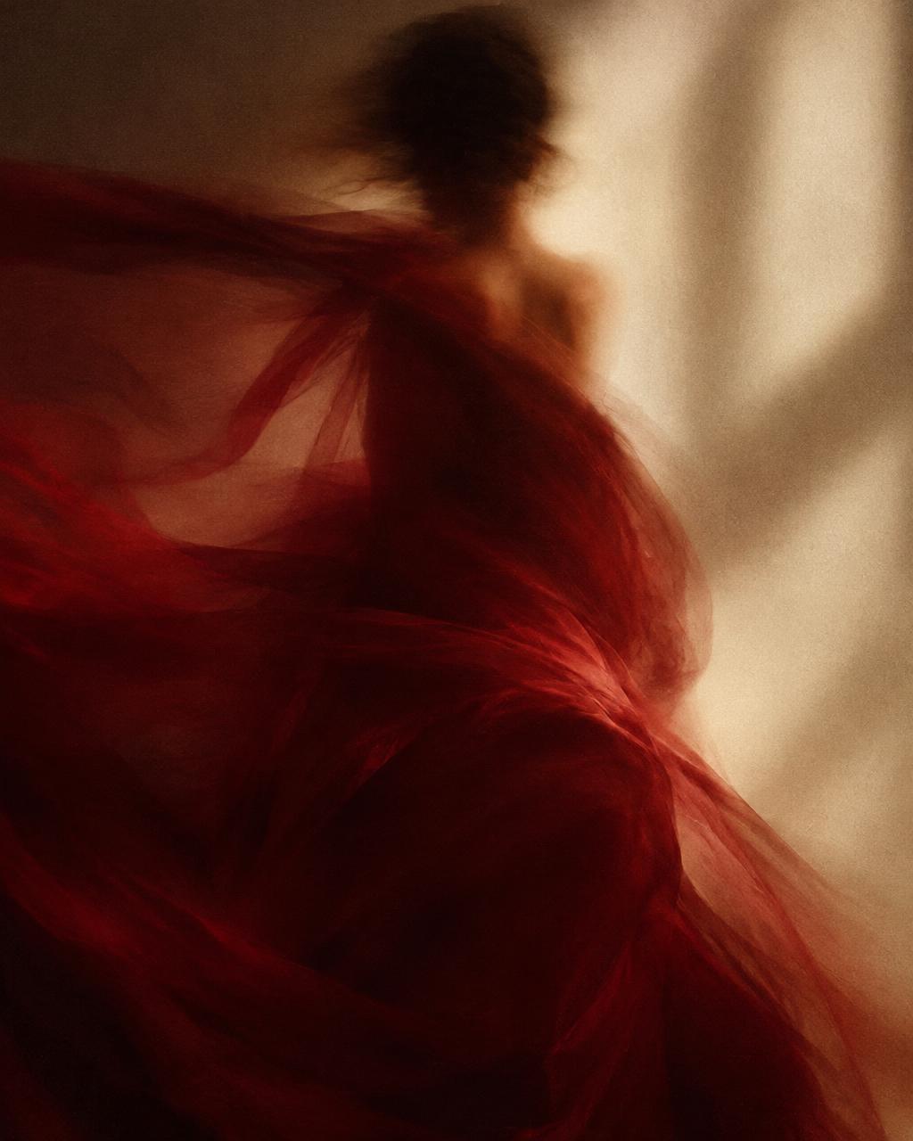 a blurred figure in deep red silk, caught in gentle motion